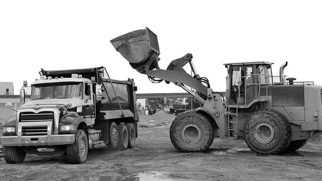 Excavator unloading materials into a dump truck on a construction site