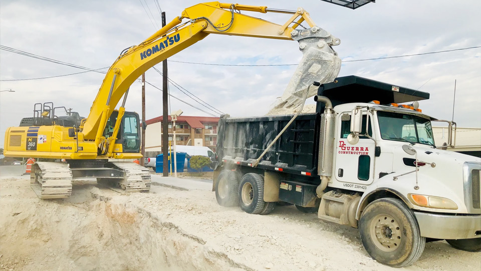 Excavator loading materials into a dump truck on a D. Guerra Construction site