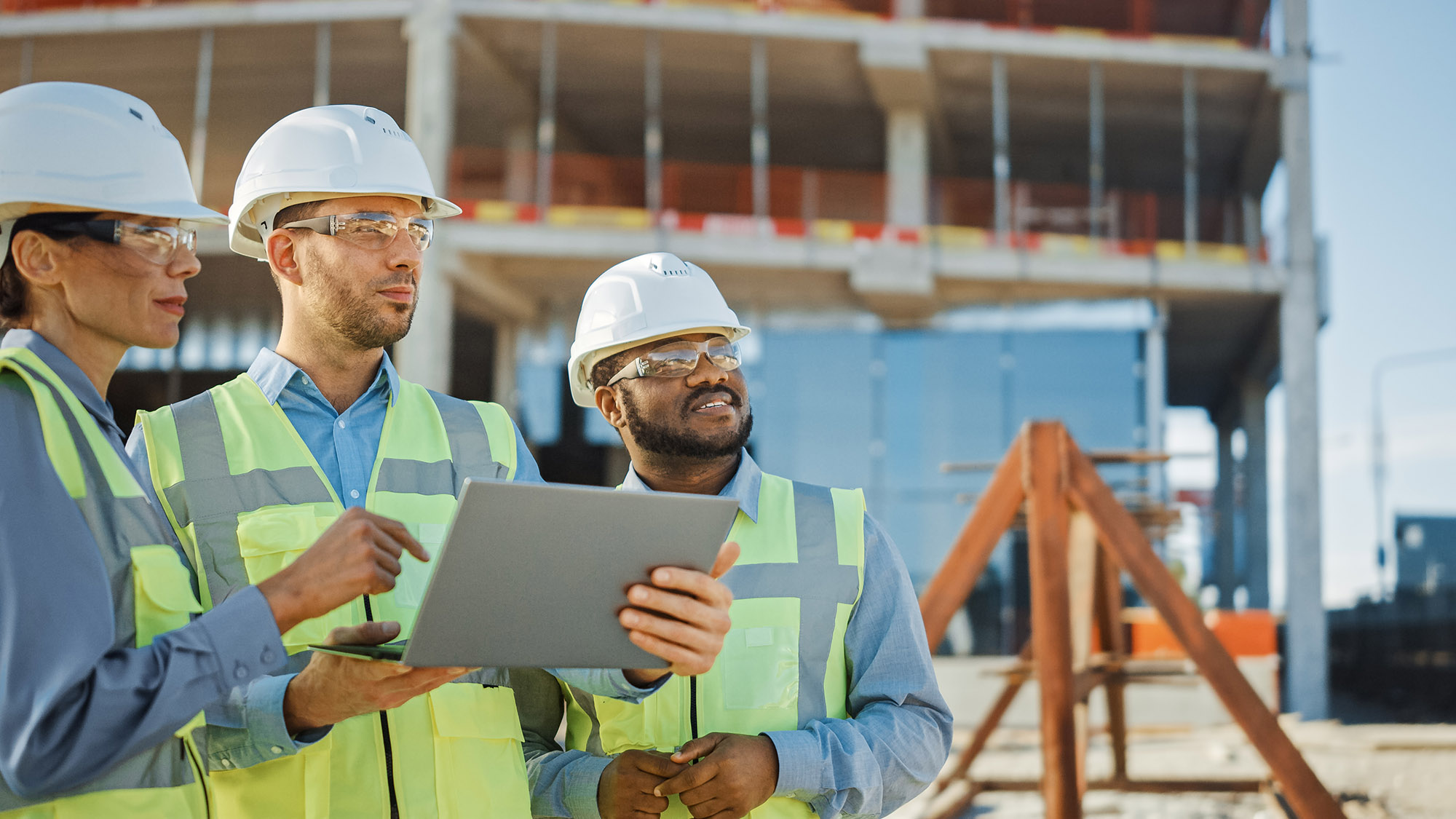 Diverse Team of Specialists Use Laptop Computer on Construction Site. Real Estate Building Project with Engineer, Investor and Businesswoman Checking Area, working on Civil Engineering, Discussing Strategy, Plan, Details.