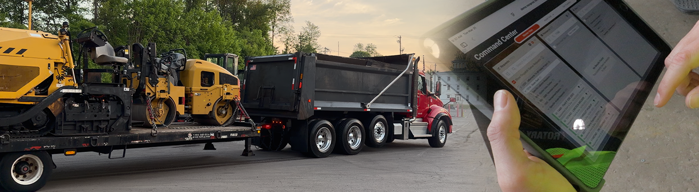 Truck hauling construction equipment and someone using construction dispatch and scheduling software on a tablet Truck hauling construction equipment and someone using construction dispatch and scheduling software on a tablet