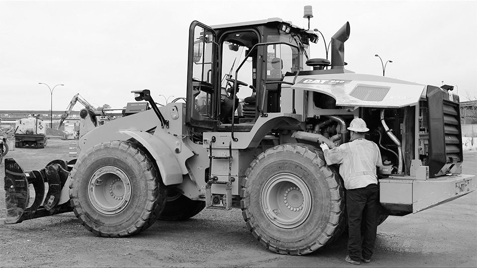 Image of a construction worker doing Equipment Inspections on a wheel loader on a construction site